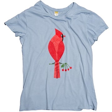 The image shows a light blue T-shirt featuring a graphic of a bright red cardinal perched on a branch with small red berries.