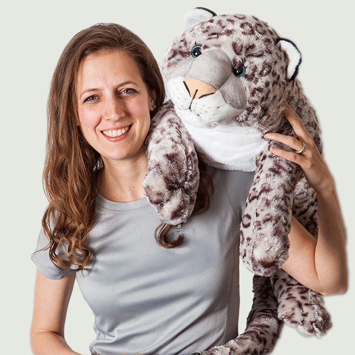 A person with long hair holds a plush snow leopard while wearing a light gray shirt.