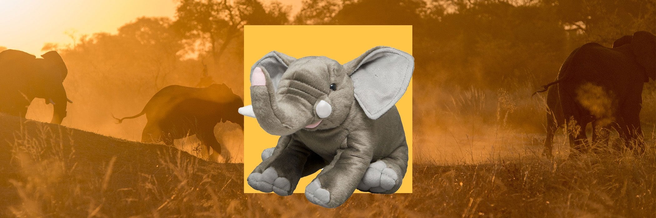 A plush gray elephant toy is centered against a yellow background, with a blurred image of elephants in a savanna setting behind it.