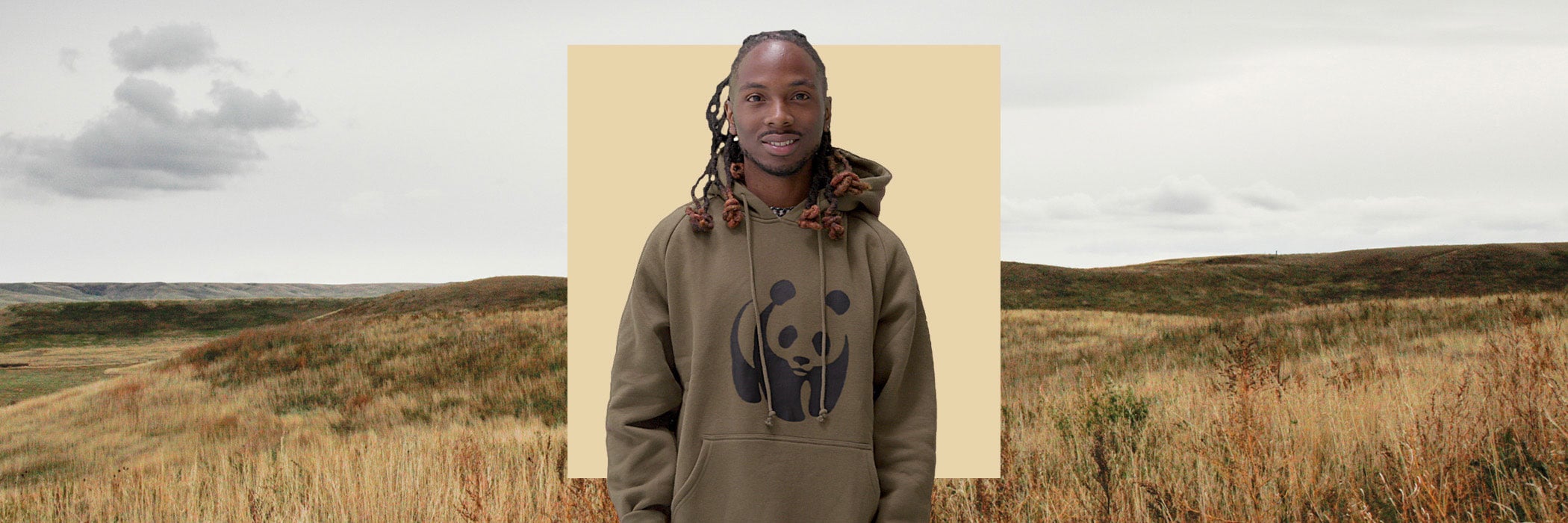 Man in green Panda Hoodie in front of yellow square in front of plains