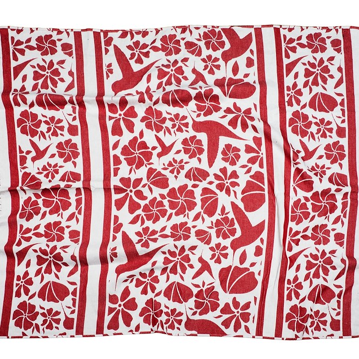 A fabric with a red and white floral and bird pattern arranged in vertical stripes.
