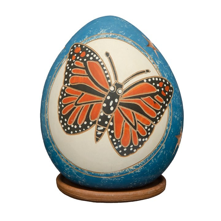 A blue and orange butterfly painted on a blue and white egg-shaped luminary