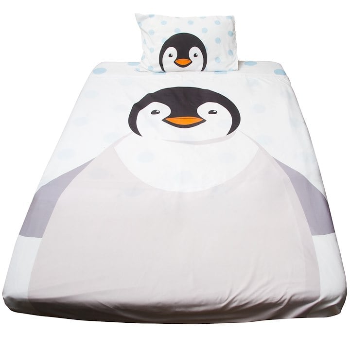 A bed with a penguin-themed duvet and pillowcase set featuring a large penguin design.